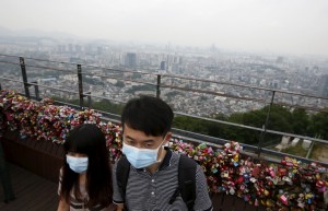A couple wearing masks to prevent contracting MERS, tours as central Seoul is seen in the background at "N Seoul Tower" located atop Mt. Namsan in Seoul