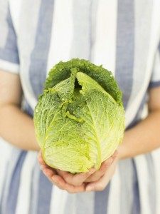 Studio shot of woman holding fresh cabbage